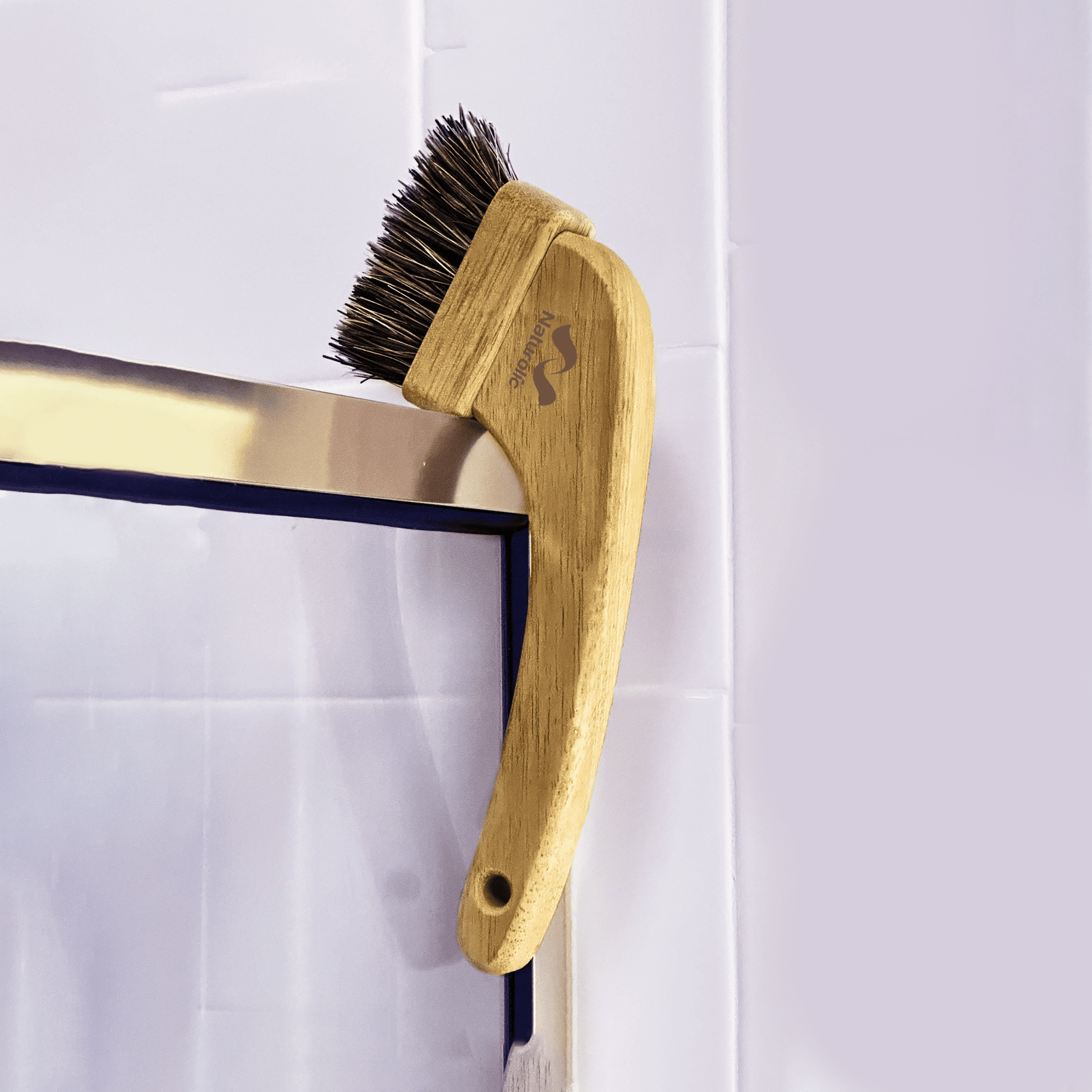 All-natural grout brush hanging on a tile, showcasing its natural wood and stiff fiber bristles.